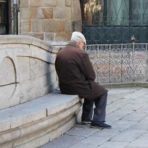 Grauhaariger Mann sitzt auf einer Bank